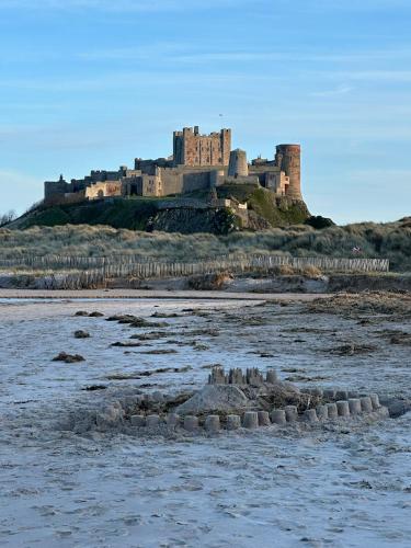 a castle sitting on top of a sandy beach at Brada View - Bamburgh, Northumberland in Bamburgh