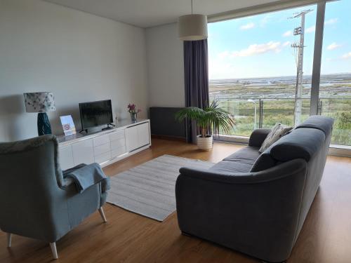 a living room with a couch and chairs and a large window at Alto das Marinhas in Aveiro
