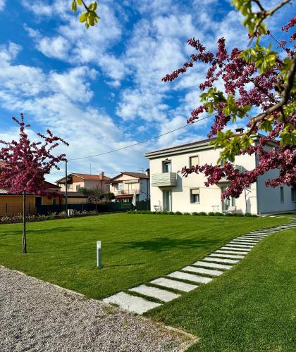 a white building on a grass field with a tree at LA ROSA DEL SILE in Quarto dʼAltino