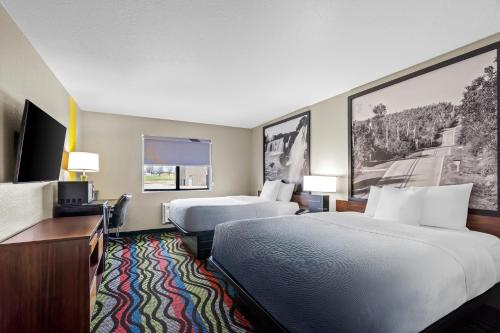 a hotel room with two beds and a desk at Super 8 by Wyndham Farmington in Farmington