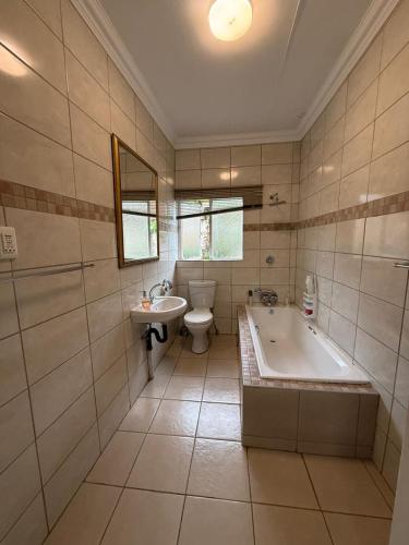 a bathroom with a tub and a toilet and a sink at Green Grove Villa in Centurion