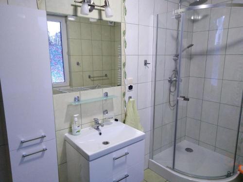 a white bathroom with a sink and a shower at Pokoje U Rycha in Augustów