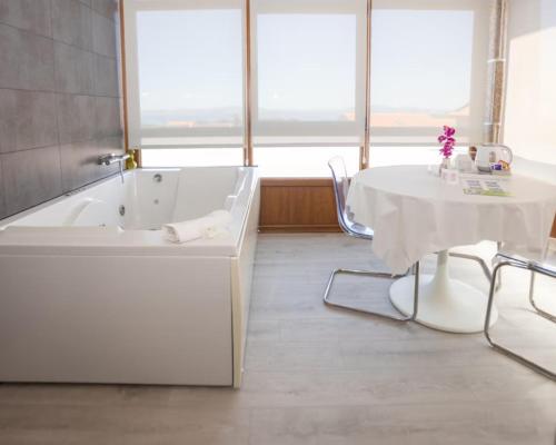 ein Badezimmer mit Badewanne und ein Tisch mit weißer Tischdecke in der Unterkunft Hotel & Apartamentos Cons da Garda in San Vicente de O Grove