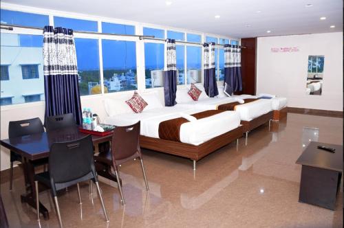 a bedroom with a large bed and a table with chairs at Metro Lodge in Chikmagalūr