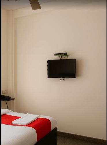 a bedroom with a bed and a tv on the wall at Metro Lodge in Chikmagalūr