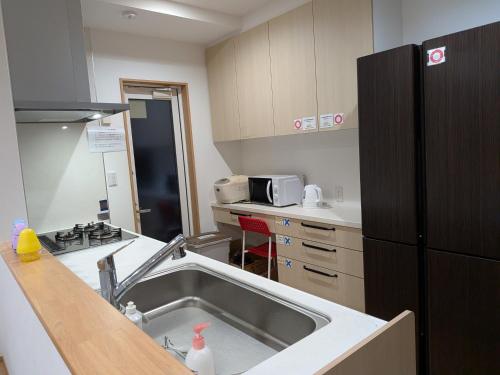 a kitchen with a sink and a refrigerator at わんぱくポケット in Tenjin