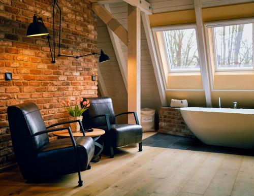 a bathroom with a bath tub and two chairs and a table at Ferienhaus Fließ Paradies mit privatem Saunahaus - Leipe, Spreewald in Leipe