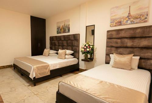 ein Schlafzimmer mit zwei Betten und Blumen darin in der Unterkunft Hotel Estevez in Chinácota