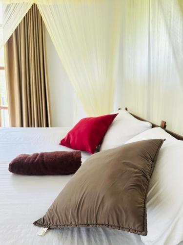 a bed with three pillows on top of it at Dacha Retreat in Midigama East