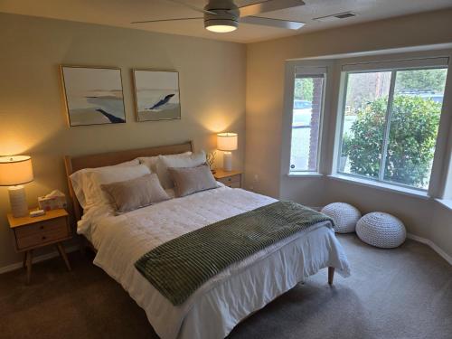 a bedroom with a bed with two lamps and two windows at Spacious Ranch Retreat Near Yosemite & Bass Lake with Hot Tub & Game Room in Oakhurst