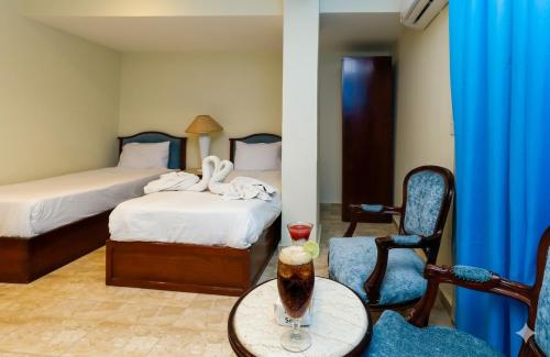 a hotel room with two beds and a table with a drink at Giza Pyramids Hotel in Cairo