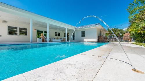 a swimming pool with a fountain in front of a house at Tranquility Villa Heated Pool & Lanai in Jupiter