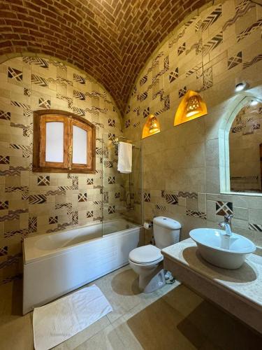 a bathroom with a tub and a toilet and a sink at Sahari house in Al Aqālitah