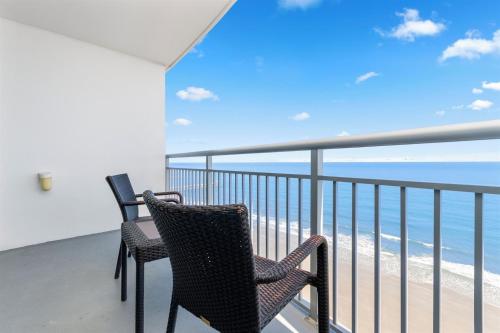 two chairs sitting on a balcony overlooking the ocean at Modern Decor Stunning Ocean View Condo Sleeps 8 in Myrtle Beach
