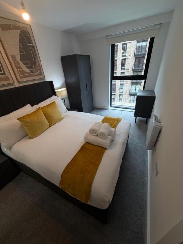 a bedroom with a large bed with two towels on it at Berkeley Square Apartments by StaySavvy Accommodation in Manchester