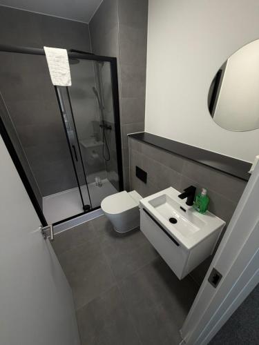a bathroom with a shower and a toilet and a sink at Berkeley Square Apartments by StaySavvy Accommodation in Manchester