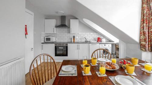 a kitchen with a wooden table with food and orange juice at Bute Seaview in Rothesay