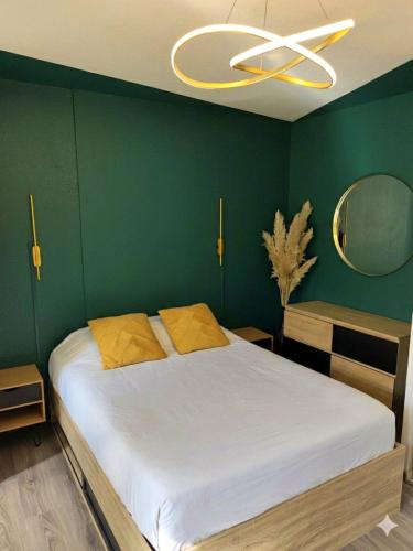 a bedroom with a large bed with a green wall at Studio les Hauts de Honfleur in Équemauville