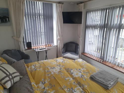 a bedroom with a yellow bed and two windows at The Bolt Hole in Barmouth
