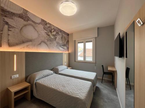 a bedroom with a bed and a desk and a television at Appartamento Ideal con piscine e animazione Hotel Alba d Oro estate in Gatteo a Mare