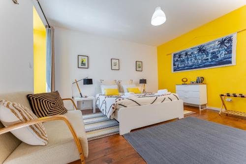 a bedroom with a bed and a yellow wall at A-Típica GuestHouse in Ponta Delgada