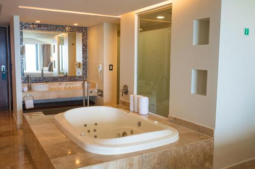 a large bathroom with a tub and a large mirror at Azul Ixtapa Grand All Inclusive Suites - Spa & Convention Center in Ixtapa