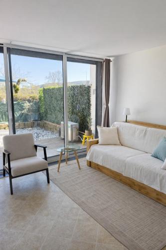 a living room with a white couch and a chair at Le Paradis' c'est ici in Gréoux-les-Bains