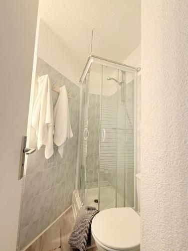 a bathroom with a toilet and a shower with towels at Terrasse vue Etang, piscine Séjour détente in Le Barcarès