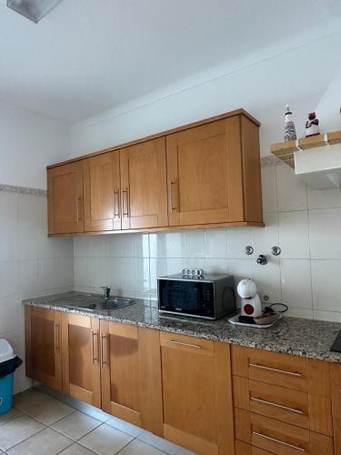 una cucina con mobili in legno e un forno a microonde di Vila Mar Central ad Albufeira
