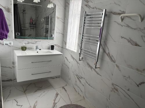 a white bathroom with a sink and a mirror at Varpholt House Apartments & Rooms in Akureyri