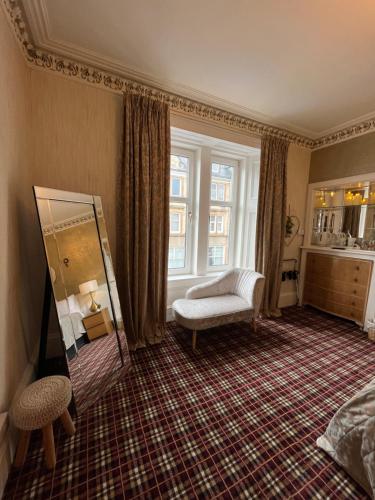 a bedroom with a mirror and a chair and a window at The Lili & Orchid Guesthouse in Oban