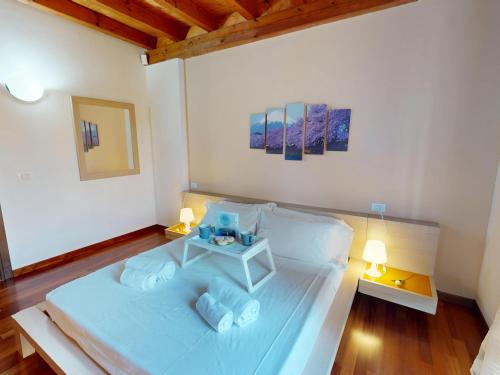 a bedroom with a large white bed with two lamps at Sakura House By Bookinggardalake in Moniga