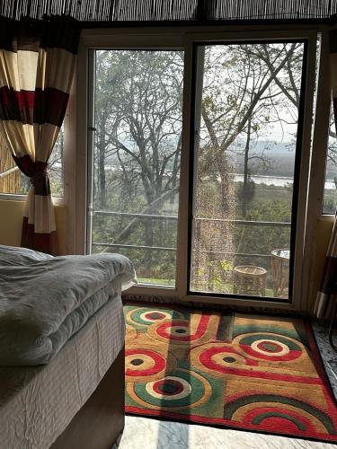 a bedroom with a large window and a rug at Jungle Nirvana Retreat in Meghauli
