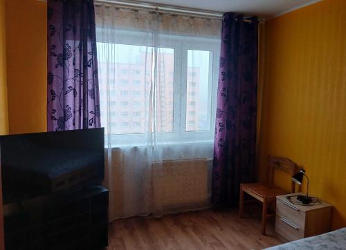 a bedroom with a large window with purple curtains at Anni Apartment in Tallinn