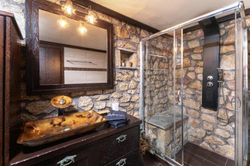 a stone bathroom with a sink and a shower at Stone Village Skala Maries in Skala Marion