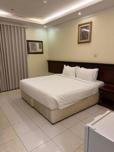 a bedroom with a large bed with white sheets at واحة الاحساء للشقق المخدومة in Al Hofuf