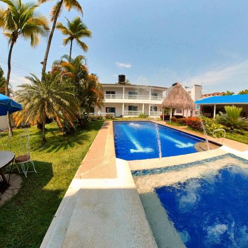a swimming pool in front of a house with palm trees at Hotel terranova in Melgar