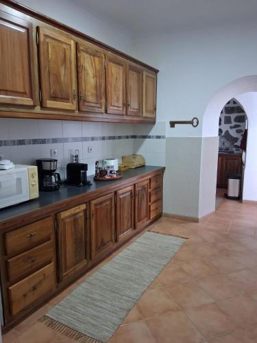 a kitchen with wooden cabinets and a microwave at Casa Galante in Furnas