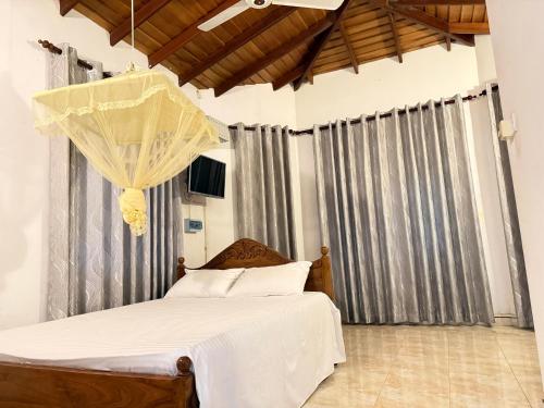 a bedroom with a bed with white sheets and curtains at Arora Villa in Digana