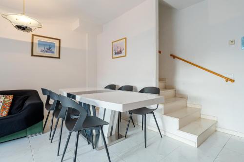 a dining room with a white table and black chairs at Hauzify I Casa Arboç in Platja d'Aro