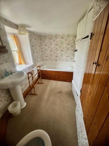 a bathroom with a bath tub and a sink at Cissy's Cottage in Hawes