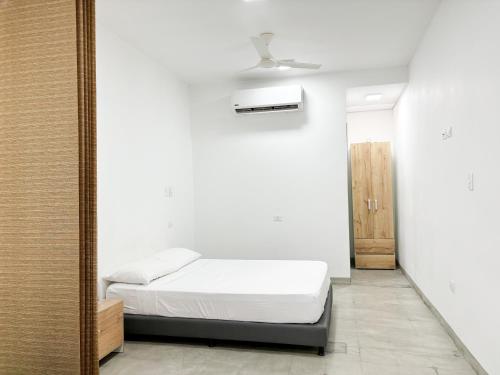 a white bedroom with a bed and a mirror at Loft del Río - Apartaestudio Completo - Aire Acondicionado, Parqueadero, WiFi, Pet Friendly in Honda