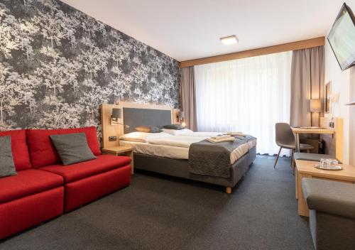 a hotel room with a bed and a red couch at Hotel Kamzík *** in Malá Morávka