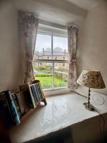 a window in a room with a lamp and books at Cissy's Cottage in Hawes