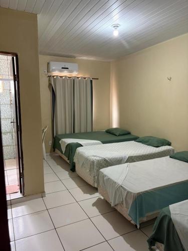 a bedroom with two beds and a window at Hotel R Soares 2 in Carutapera