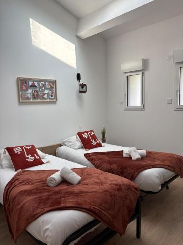 three beds in a room with red and white pillows at La Claverie in Cholet