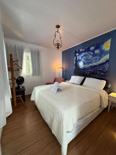 a bedroom with a large bed with a painting on the wall at Casa na "Villa Grega" pertinho do Parque Nacional, Feirinha do Alto e Granja Comary in Teresópolis