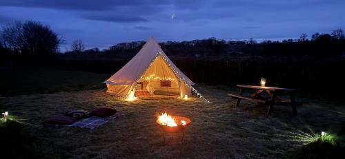 a tent with a table and fires in a field at Hinton land glampsite in Peterchurch