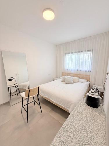 a white bedroom with a bed and a desk at וילת Velizabeth in Omen