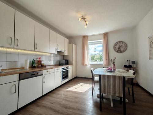 a kitchen with white cabinets and a table in it at Ferienwohnung am Ellerbach in Hessisch Oldendorf